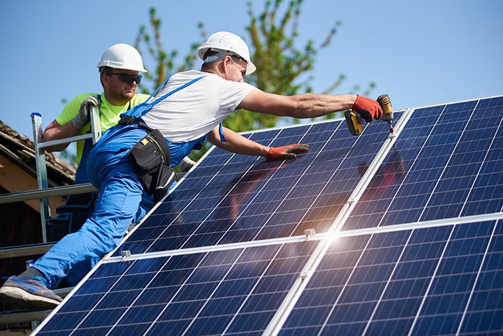 Two technicians installing solar panels. 